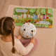 A young girl playing a Sound of Silence steel tongue drum alongside its illustrated musical storybook
