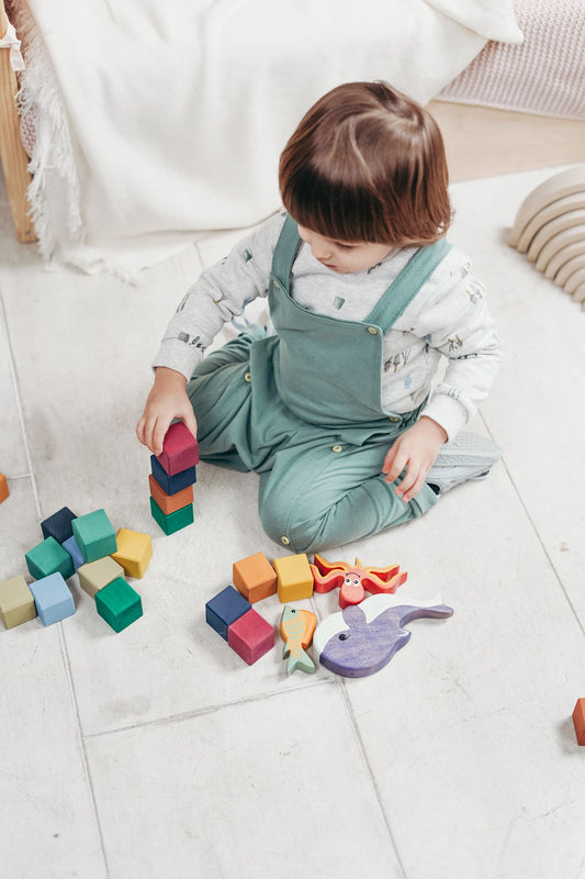 A young child playing safely with colourful non-toxic wooden toys at home