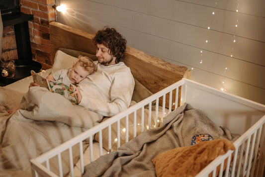 A father reading a bedtime story to his young child in a warmly lit bedroom